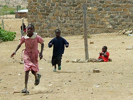 Niños corriendo hacia las furgonetas de los turistas