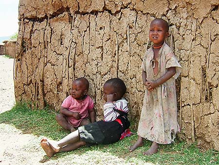 Niños masais apoyados en la pared de una choza